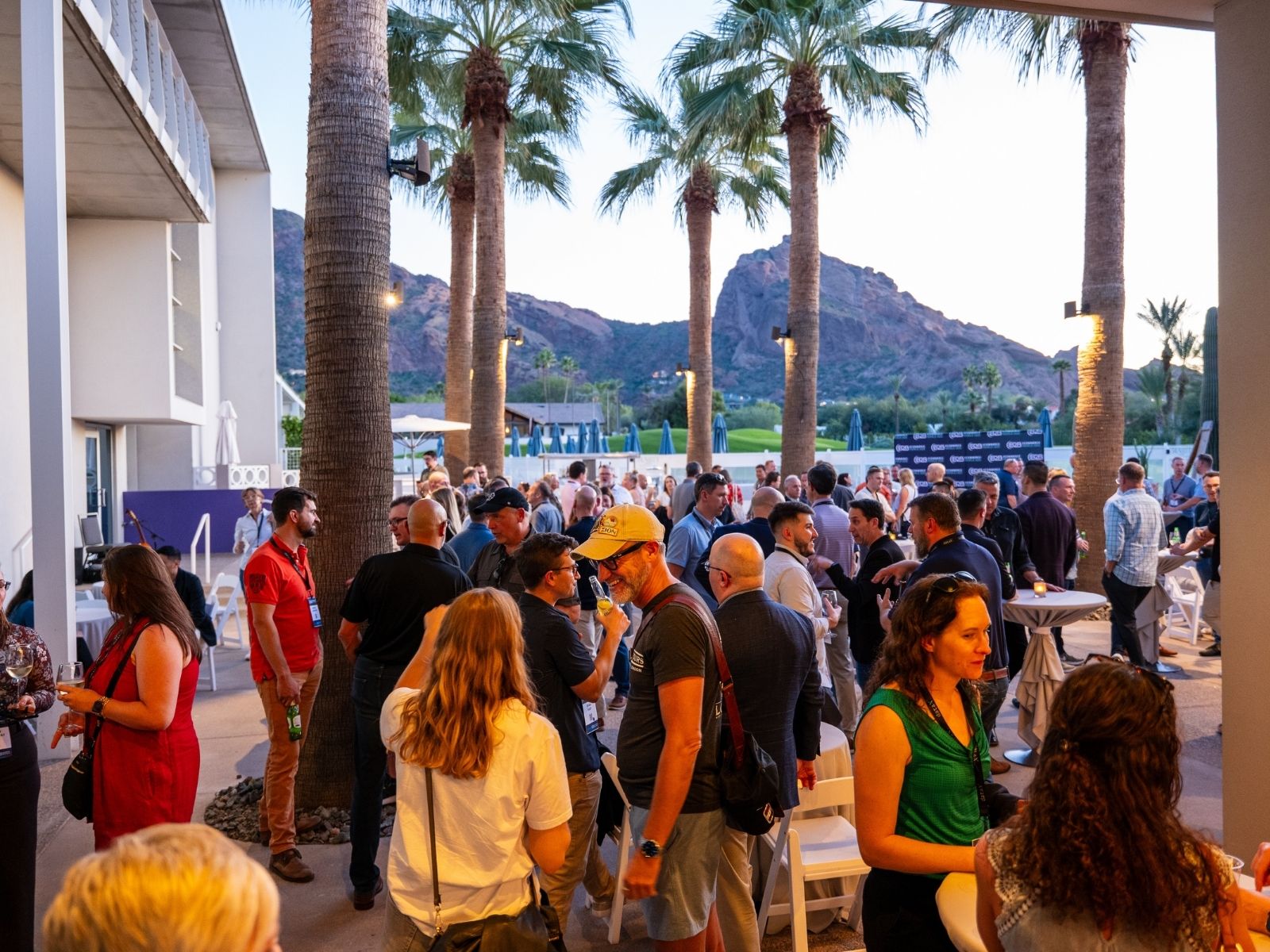 B2B eCommerce Association attendees networking at an outdoor evening event with palm trees and desert mountain backdrop