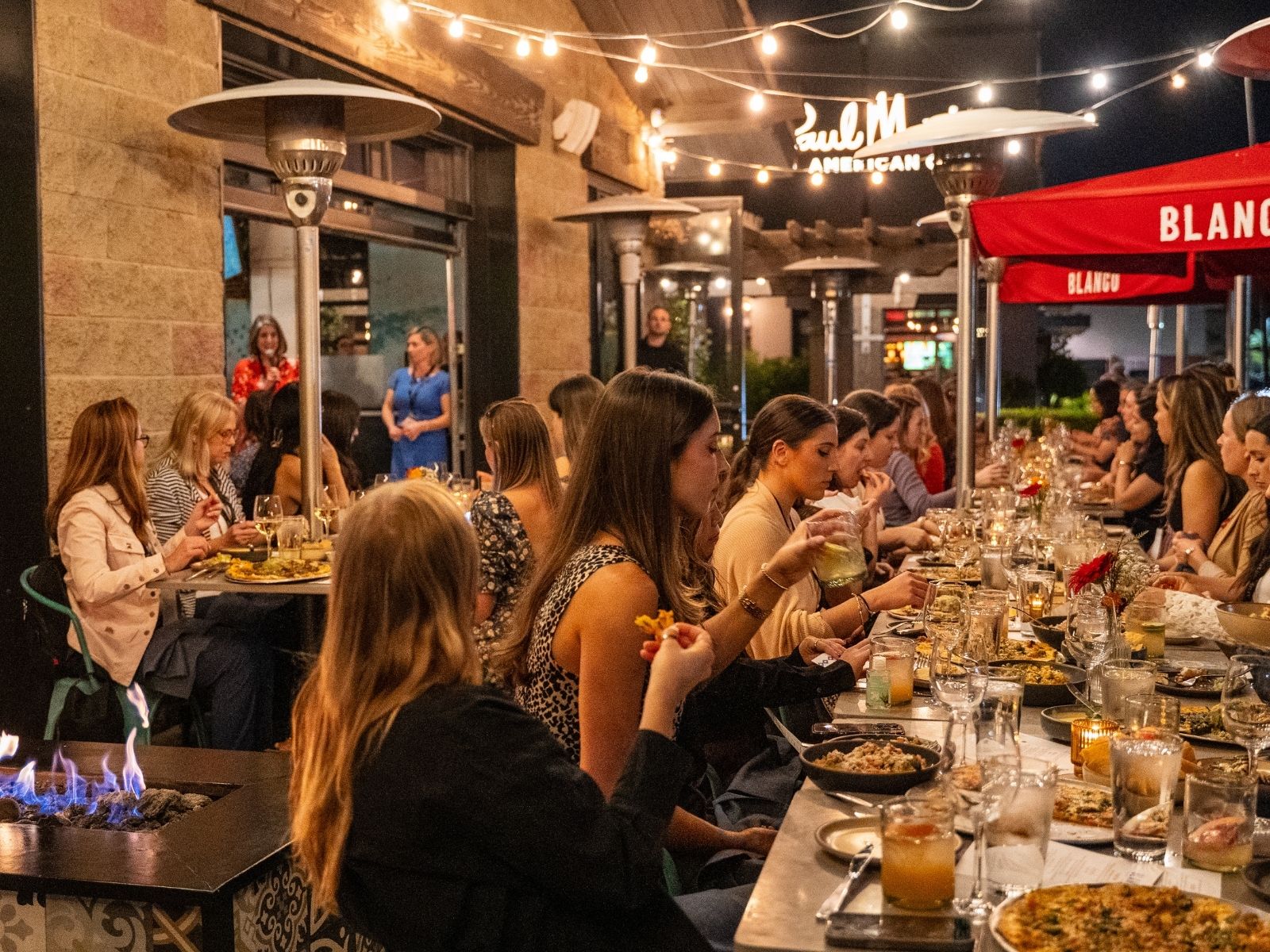Women in B2B community dinner event with attendees around a long candlelit table